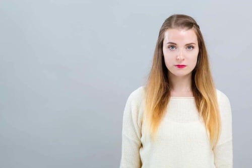 tightlipped woman against a grey background thinking about addiction to household items and inhalants