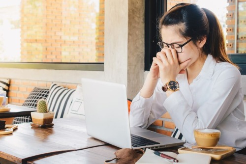 woman cries while using a computer to learn about damage from addictive behavior