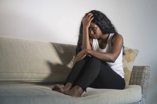 Woman feeling down sitting on a couch thinking about drug overdose symptoms