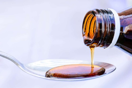 drug syrup pours onto a spoon showing an example of schedule 5 drugs