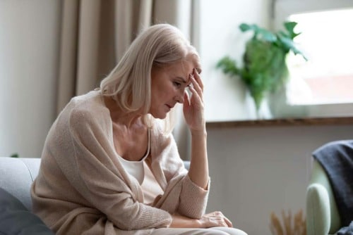 older woman holding head suffering side effects of methadone use