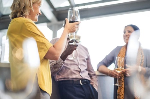 woman toasts two friends with a glass of wine exhibiting the answer to the question what is a functioning alcoholic