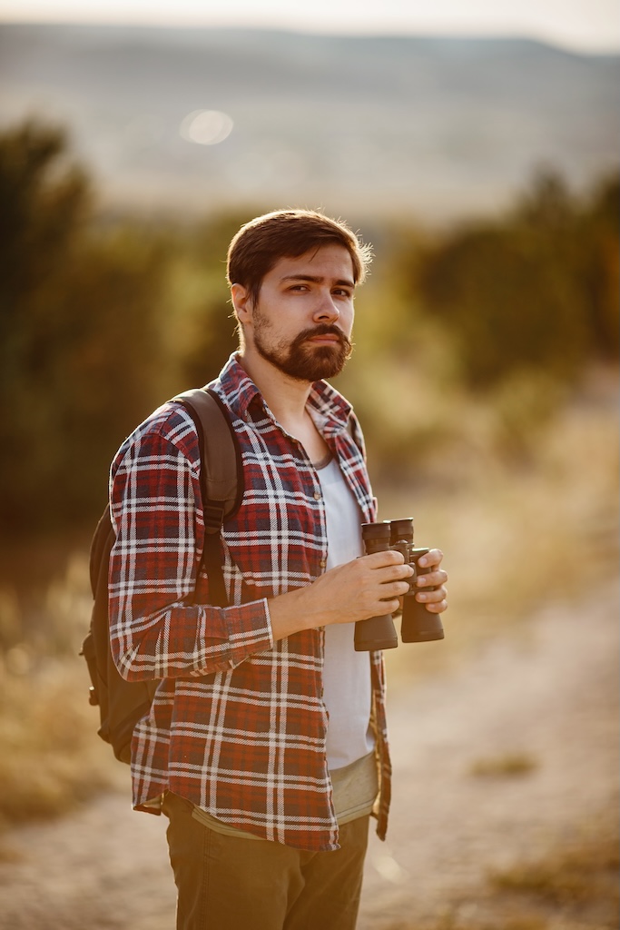 Guy looking at binoculars in hill.