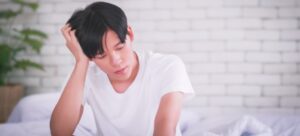 Worried young man sitting in bed.