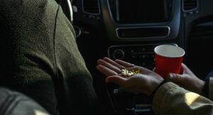 Two people sitting in a car with pills in hand