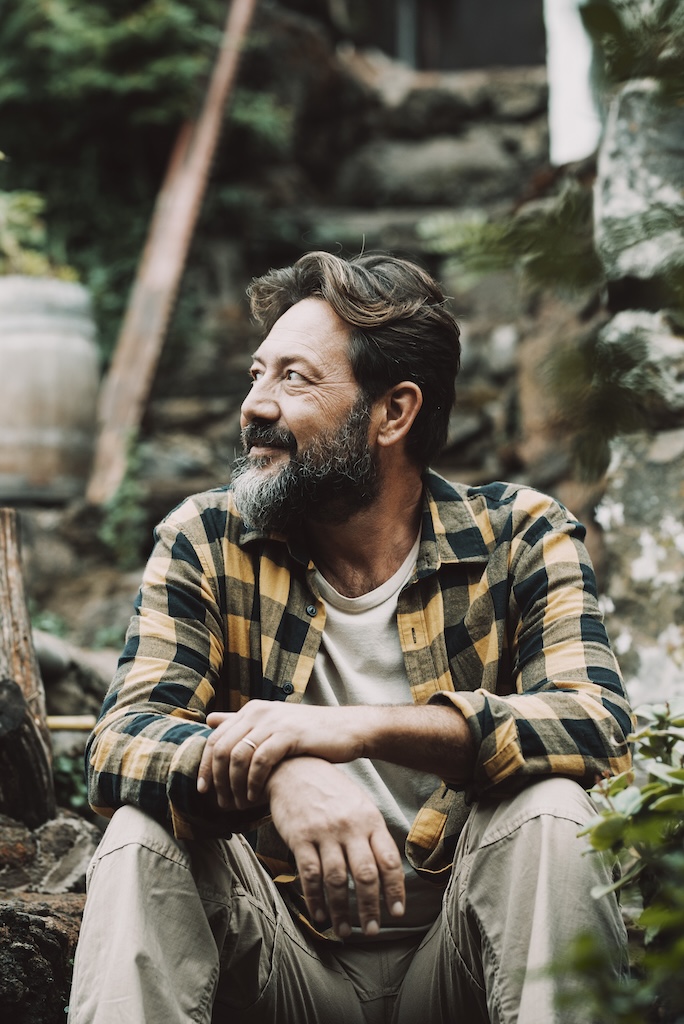 One happy and serene adult man sitting outdoor in the green nature garden.
