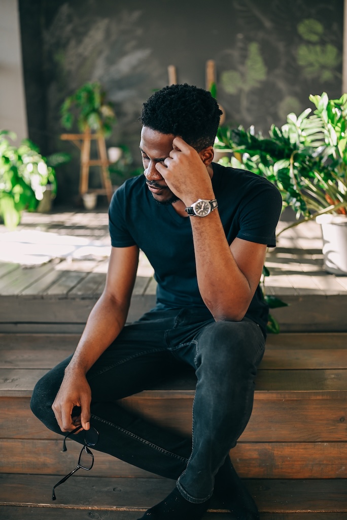 Young man sitting on old steps, looking depressed, struggling internally