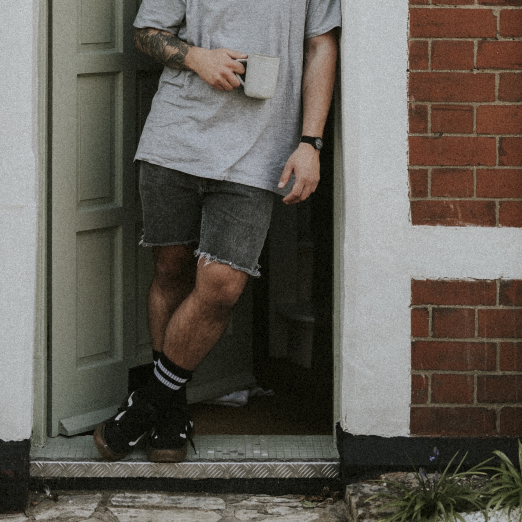 Man having a coffee by his doorway, watching the outside world