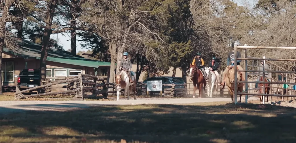 Riders on horseback on a wooded trail at The Last Resort ranch.
