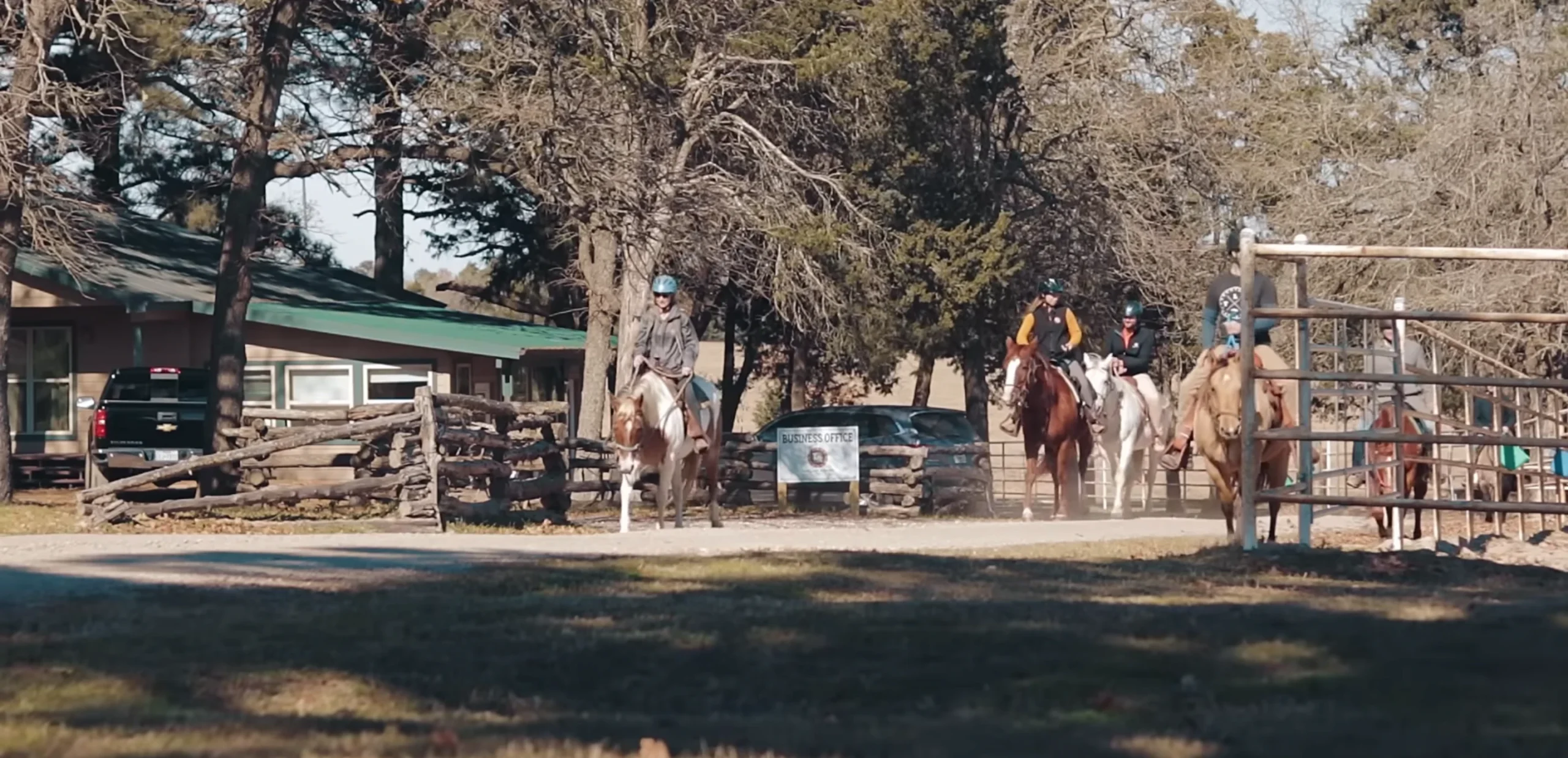 Riders on horseback on a wooded trail at The Last Resort ranch.