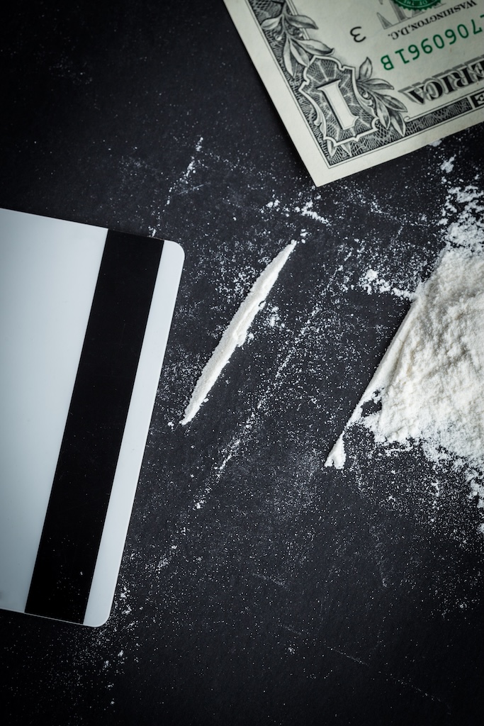What appears to be cocaine sitting next to a credit card and dollar bill on a table