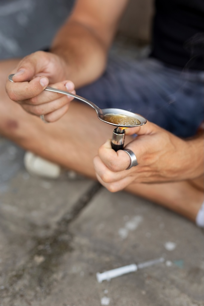 Detail of male hands cooking heroin in a spoon with a lighter