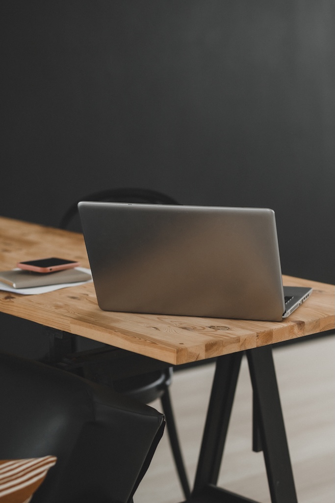 Home office with a laptop against a dark wall.